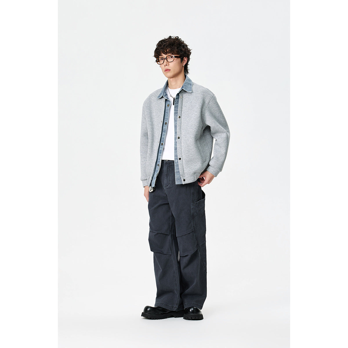 Full-length view of a model wearing a light gray denim-collar jacket, white shirt, dark cargo pants and black shoes.