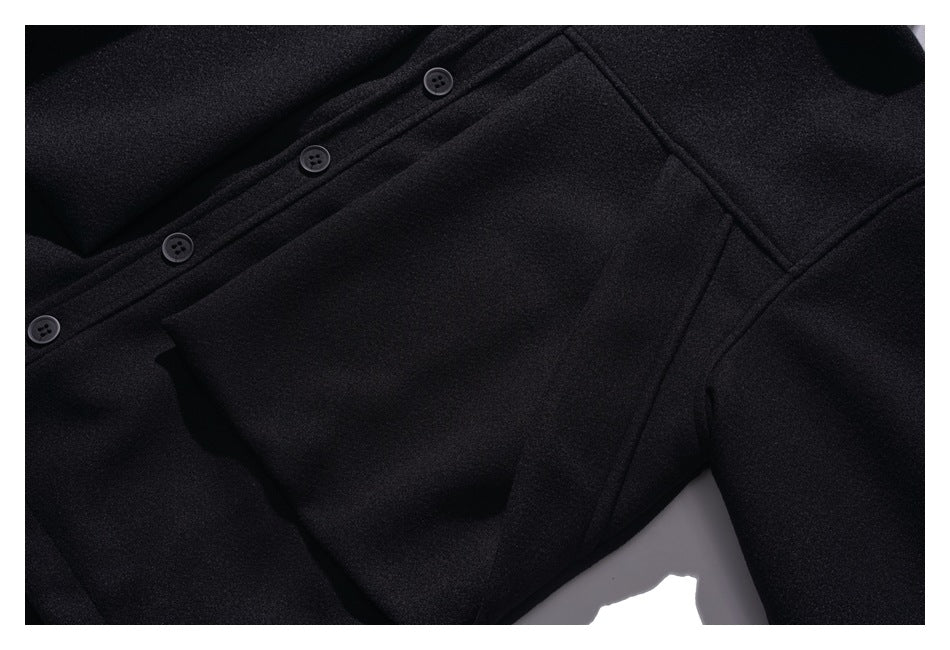 Close-up of a black coat showing its buttoned front, seam lines, and a large angled pocket.