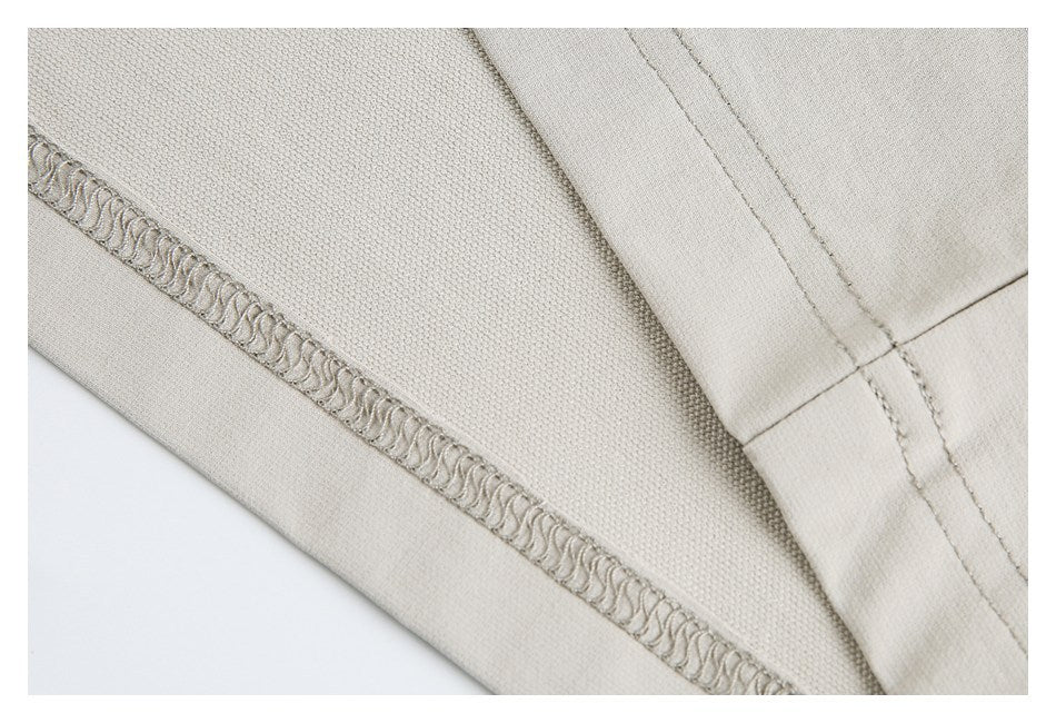 Close-up of beige garment stitching, overlocked seam, and fabric texture.