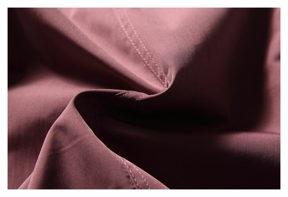 Close-up of mauve fabric folded to show its smooth surface and stitched seams.