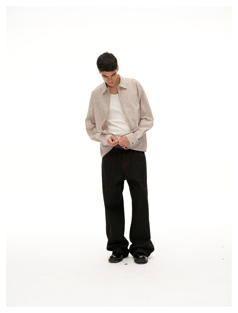 Model looking down wearing open beige striped zip shirt over a white tank top and black wide-leg jeans
