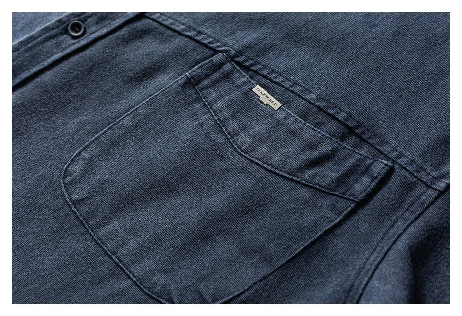 Close-up of dark indigo denim showing a stitched patch pocket, black button, and small sewn label.
