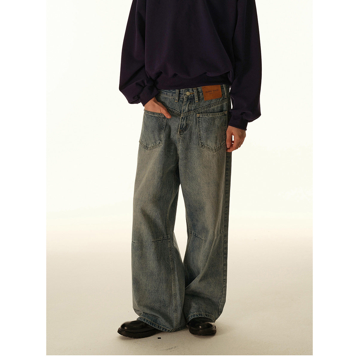 Cropped model wearing loose, faded gray wide-leg jeans with front pockets and a dark sweatshirt.