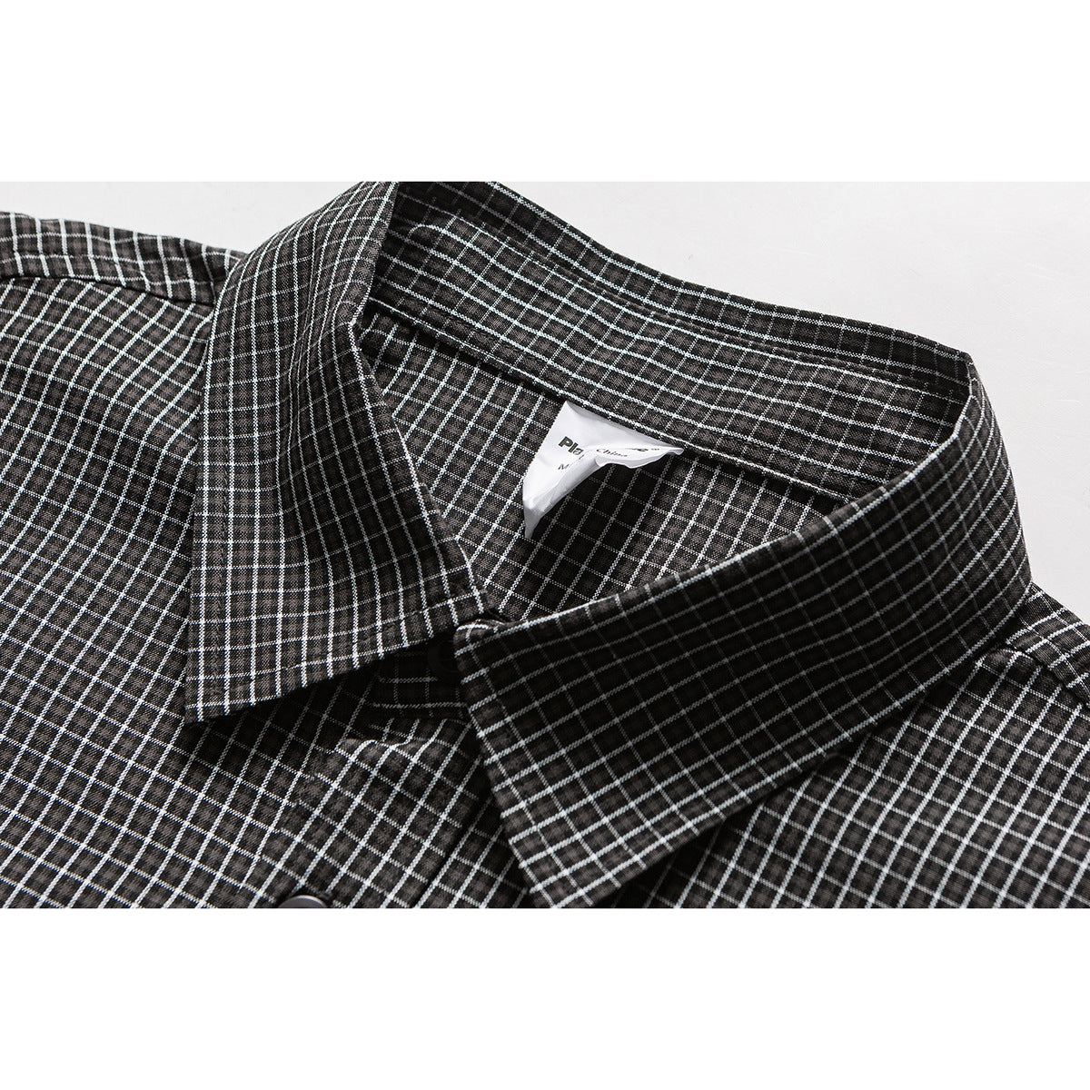 Close-up of a black shirt collar and button area with a fine white grid check.