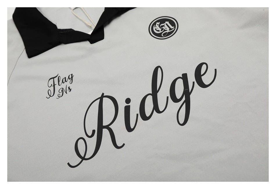 Close-up of black chest graphics and lettering on a light gray polo shirt.