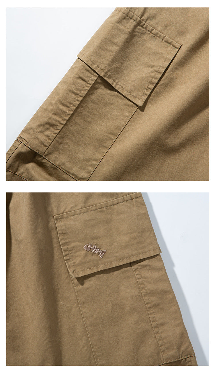 Close-up of tan cargo pants with flap cargo pockets; one pocket has a small fish embroidery.