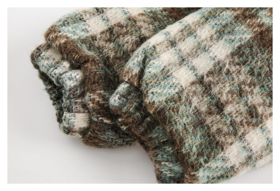 Close-up of a folded edge of a fuzzy coat in a brown, cream, and muted teal pattern.