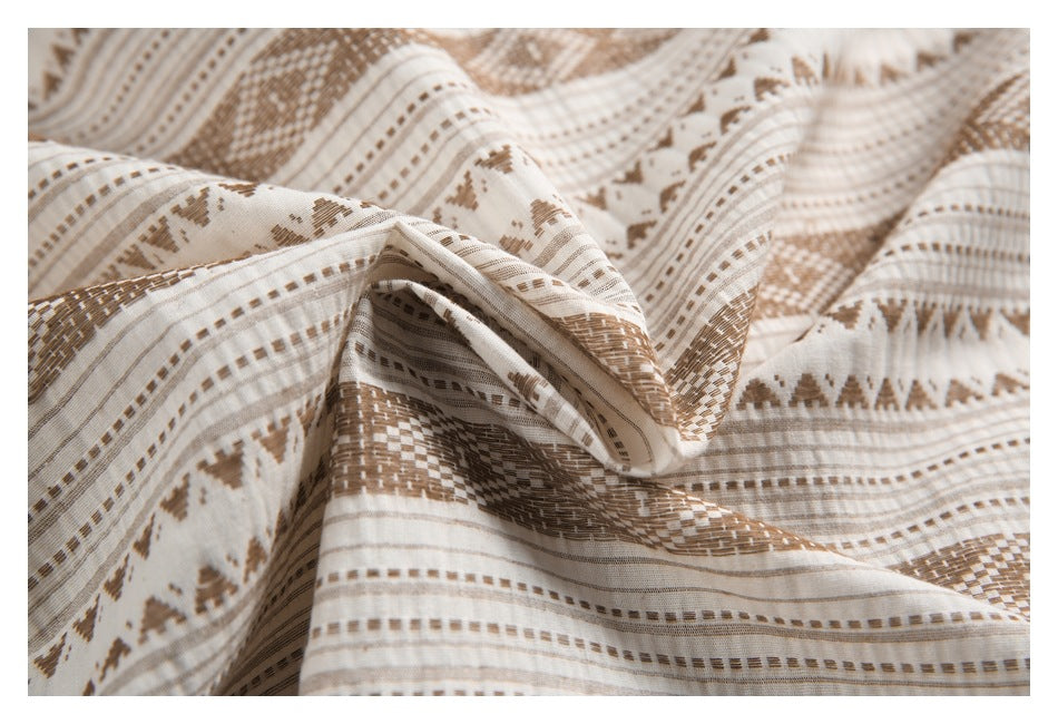 Close-up of draped cream fabric featuring repeating brown geometric stripes and textured motifs.