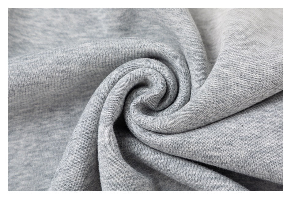 Close-up of light gray knit fabric gathered into a spiral, showing its surface texture.