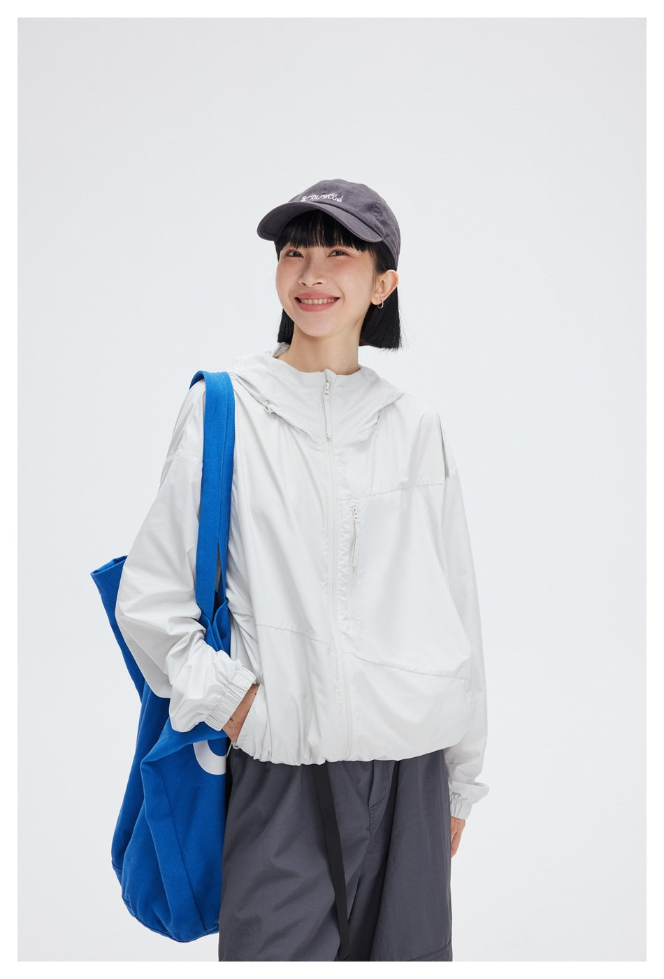 Model wearing a white zip-front hooded jacket with a chest pocket; closer view of the upper body.