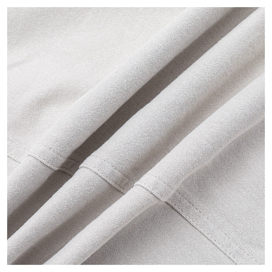 Close-up of light gray garment fabric folded to show a stitched seam.
