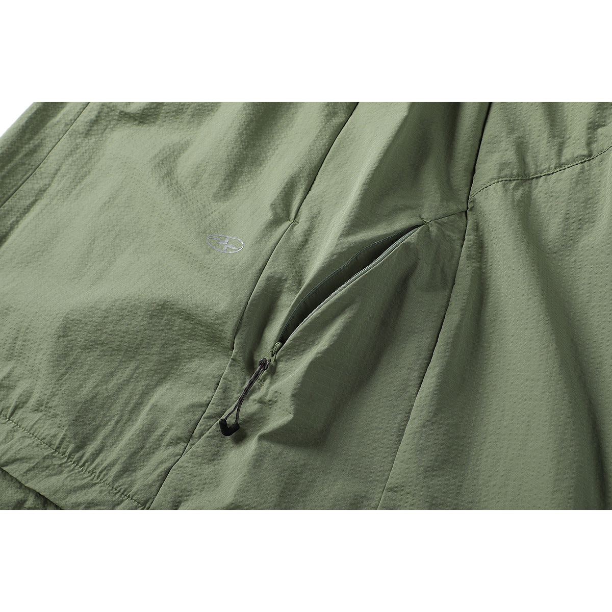 Close-up of an olive-green skirt pocket with a partly open zipper and small embroidered emblem.