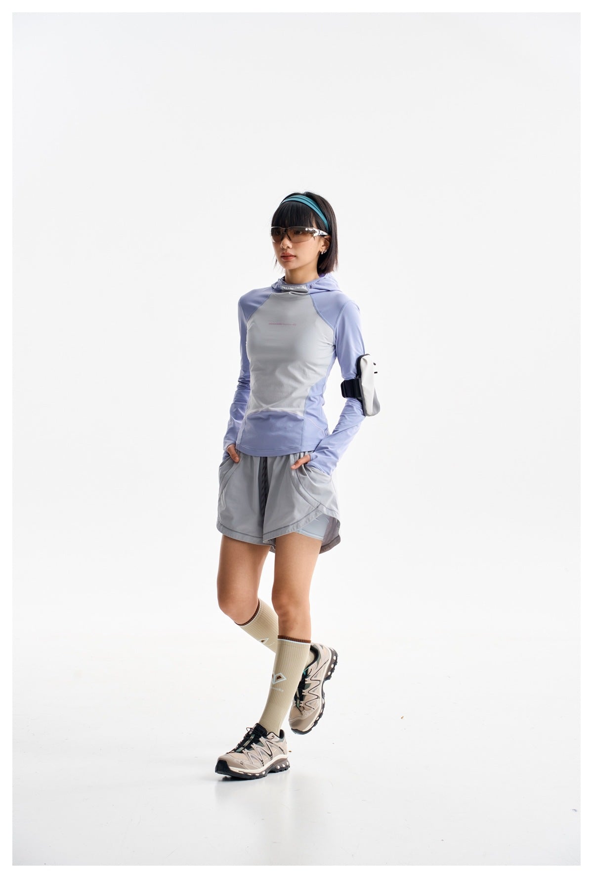 Model wearing a fitted lavender and light gray hooded top with gray running shorts, sunglasses, and knee-high socks.