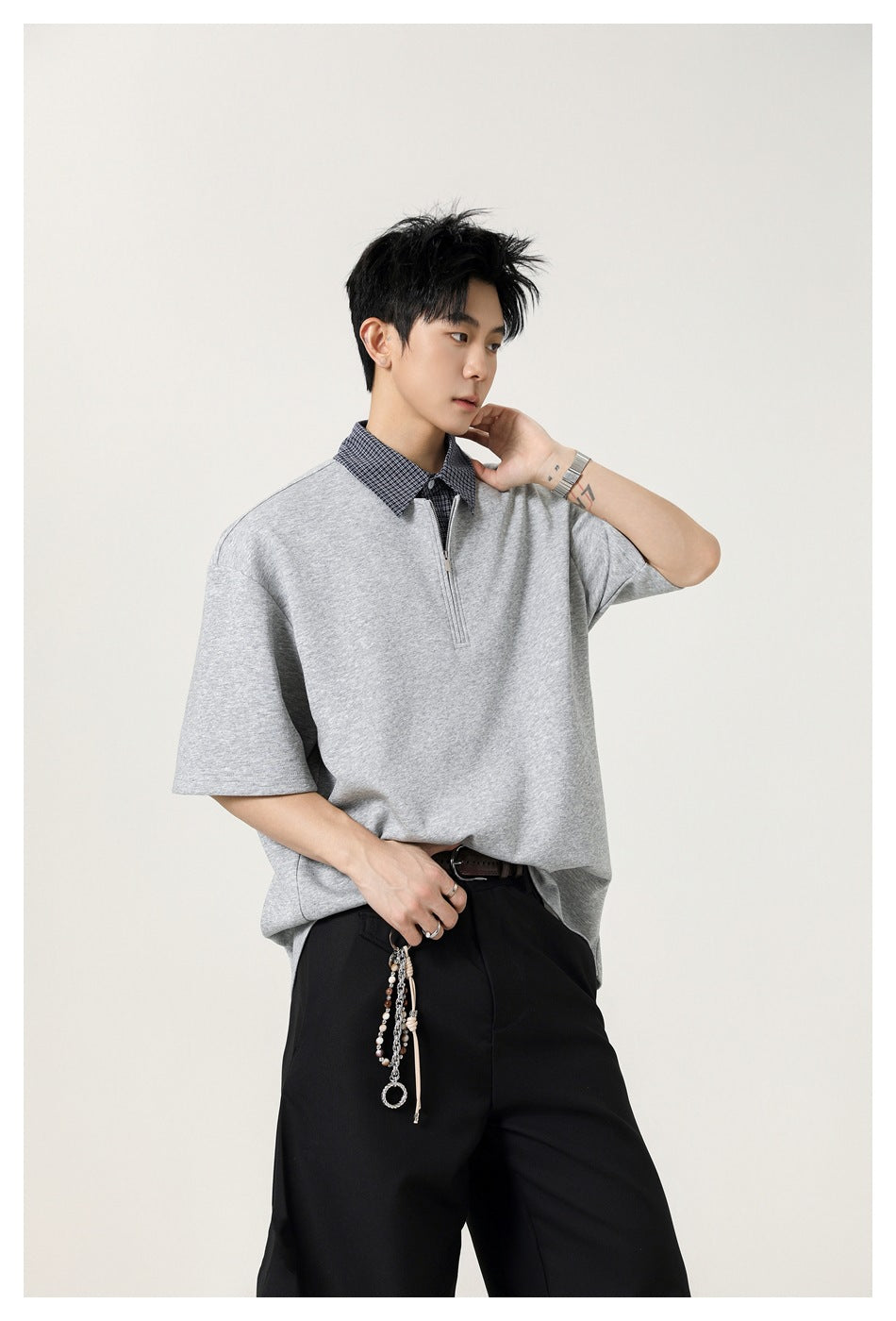 Male model wearing a light gray oversized short-sleeve top with a checked collar and short zip placket.