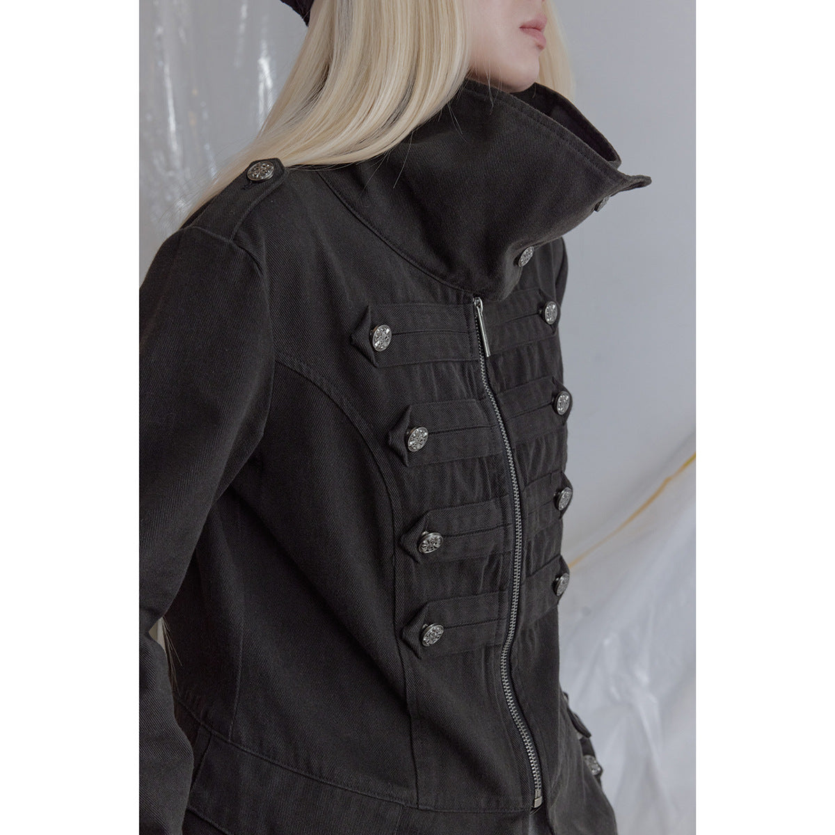 Close-up of a black jacket with a high collar, center zipper, and rows of decorative buttoned tabs.