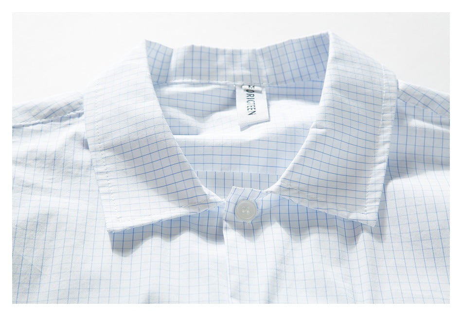 Close-up of a white shirt with a light blue grid pattern, showing the pointed collar and top button.