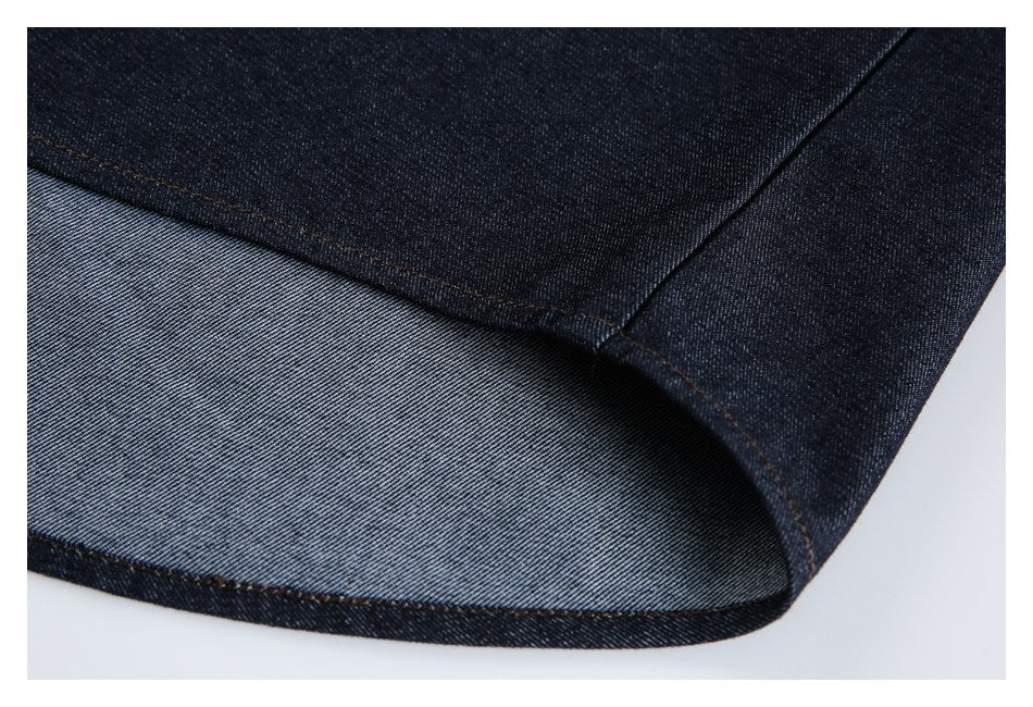 Close-up of a turned denim edge showing the lighter reverse side and stitched dark indigo outer fabric.