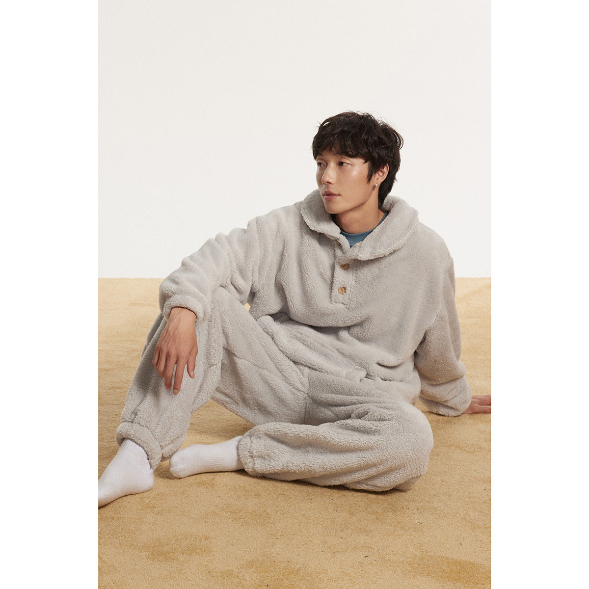Model seated in a light gray plush pullover with a wide collar and matching pants.