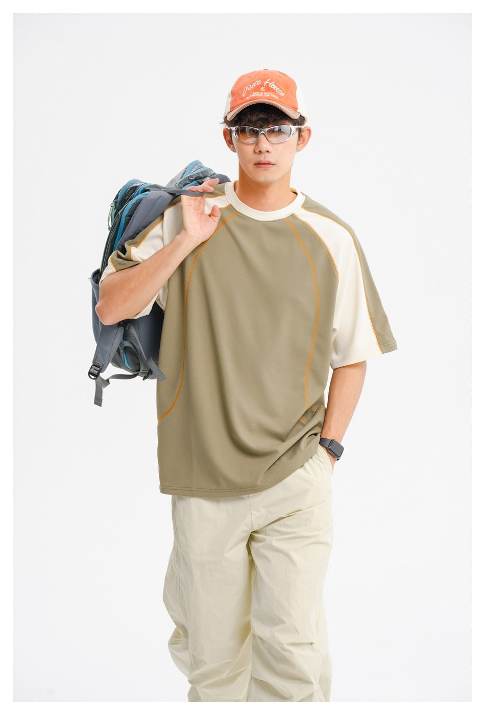Closer front view of a model wearing an olive-and-cream raglan T-shirt with contrasting orange seam lines.