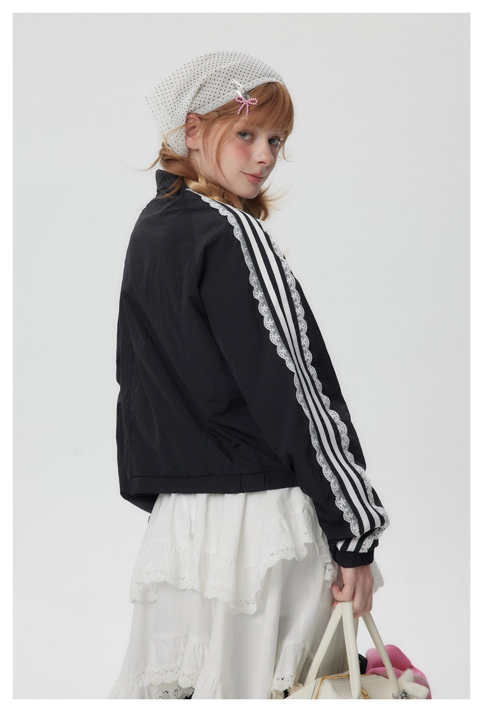 Rear three-quarter view of a model wearing a black jacket with white striped lace sleeve trim.