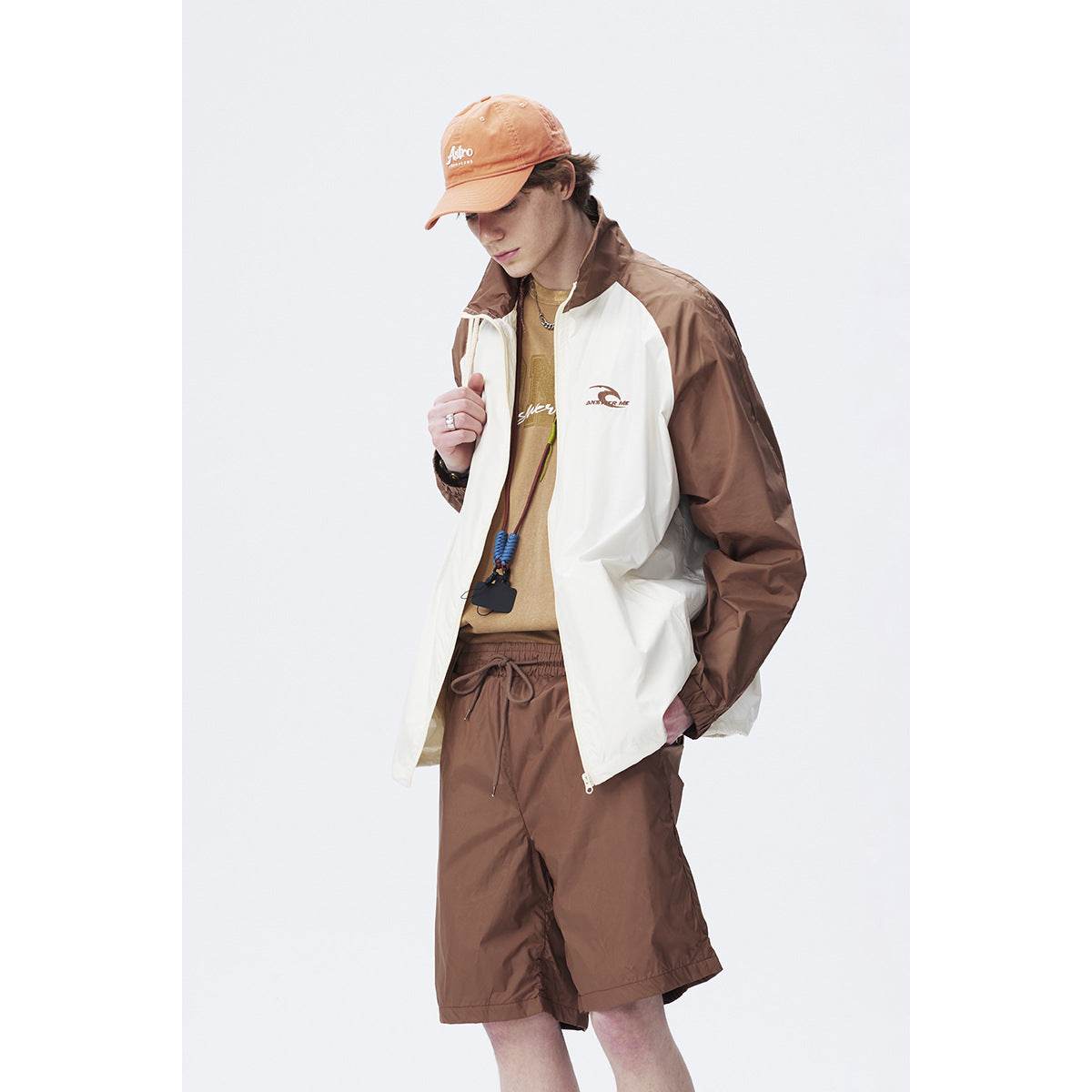 Close view of a model wearing a white-and-brown zip jacket with brown shorts.