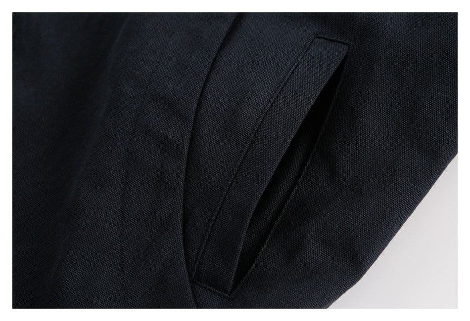 Close-up of a narrow welt pocket on dark navy fabric.