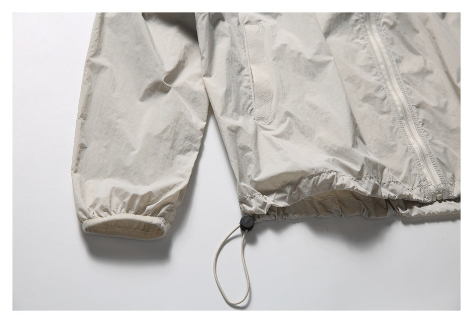 Flat-lay view of a light beige jacket with a zip front, sleeve pocket, elastic cuffs and adjustable drawcord hem.