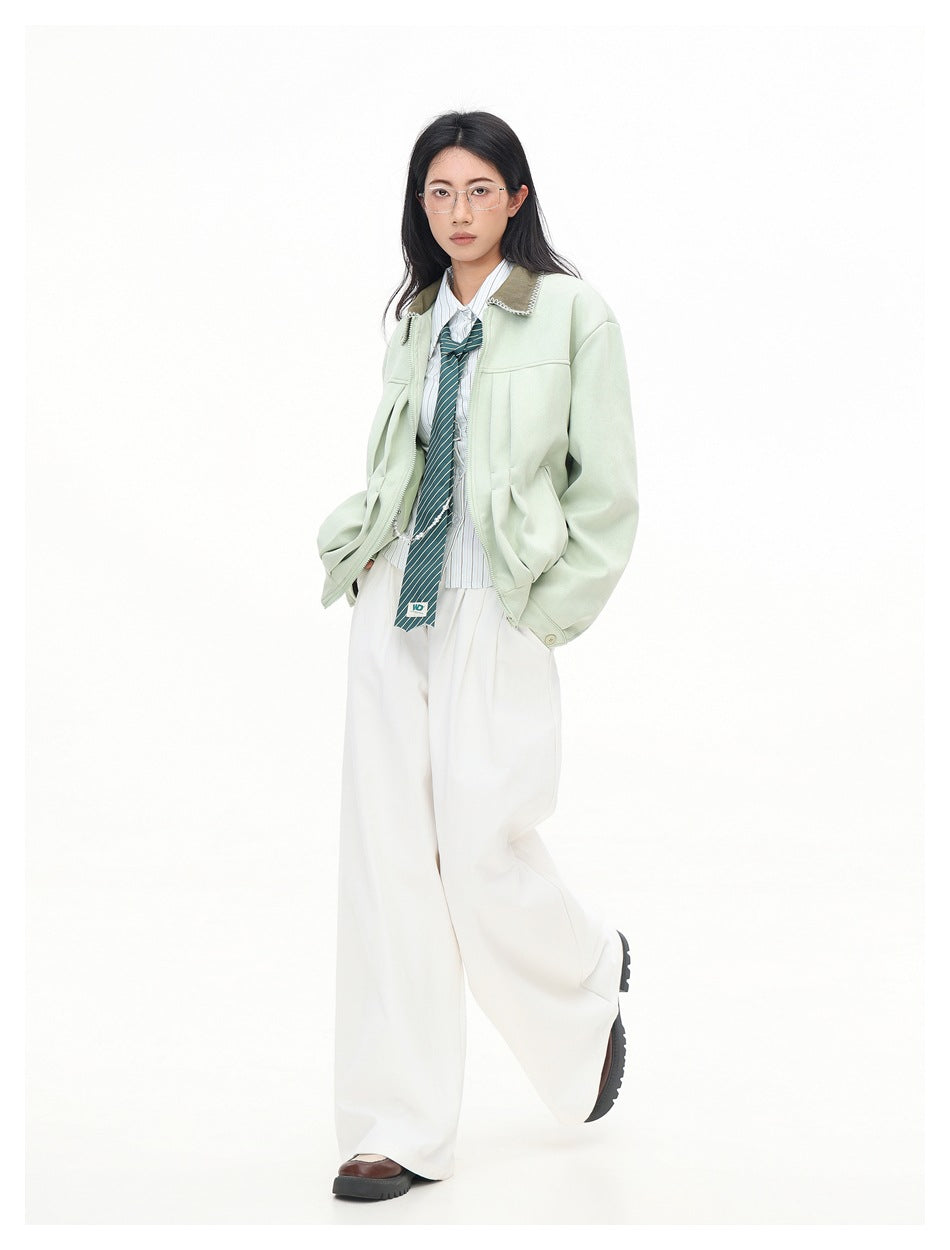 Full-length model wearing a pale mint jacket with a brown contrast collar and wide white trousers.