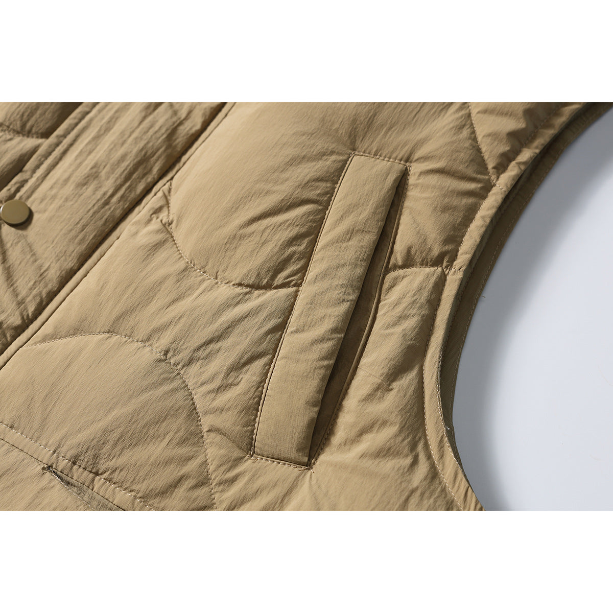 Close-up of the tan vest’s slanted pocket, curved quilting and stitched side seam.