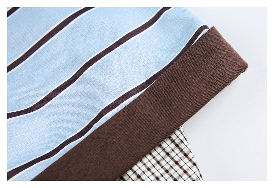 Close-up of blue striped fabric beside a solid brown band and a black-and-cream checked fabric.