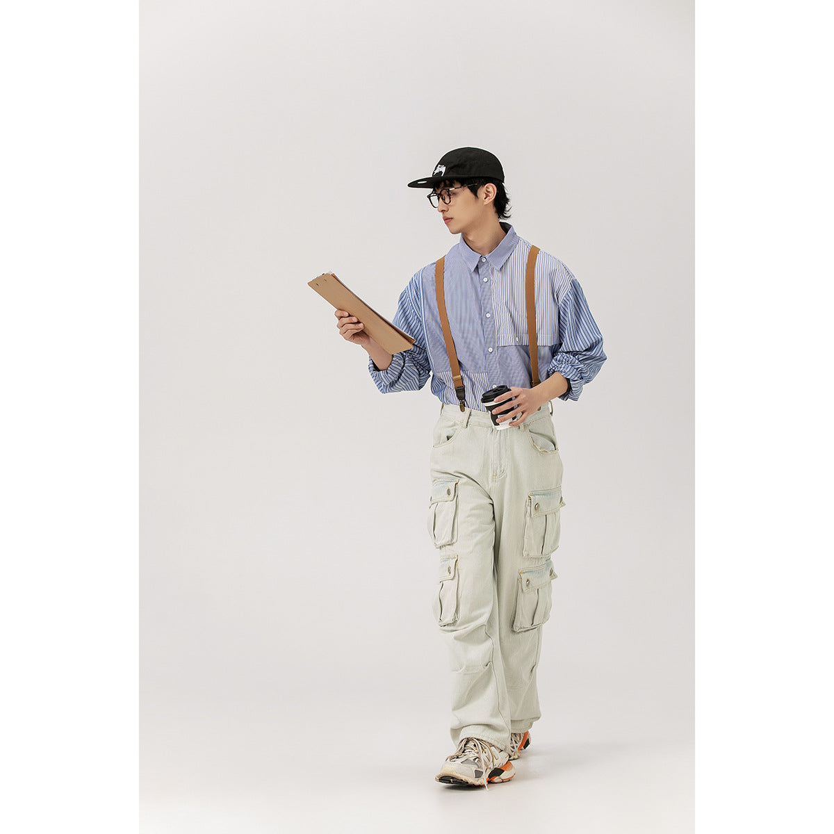 Full-length model in a blue striped patchwork shirt and pale multi-pocket cargo pants with brown suspenders.