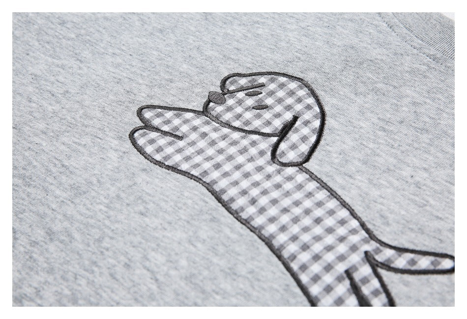 Close-up of a dog appliqué with gray-and-white gingham pattern and dark embroidered outlines on gray fabric.