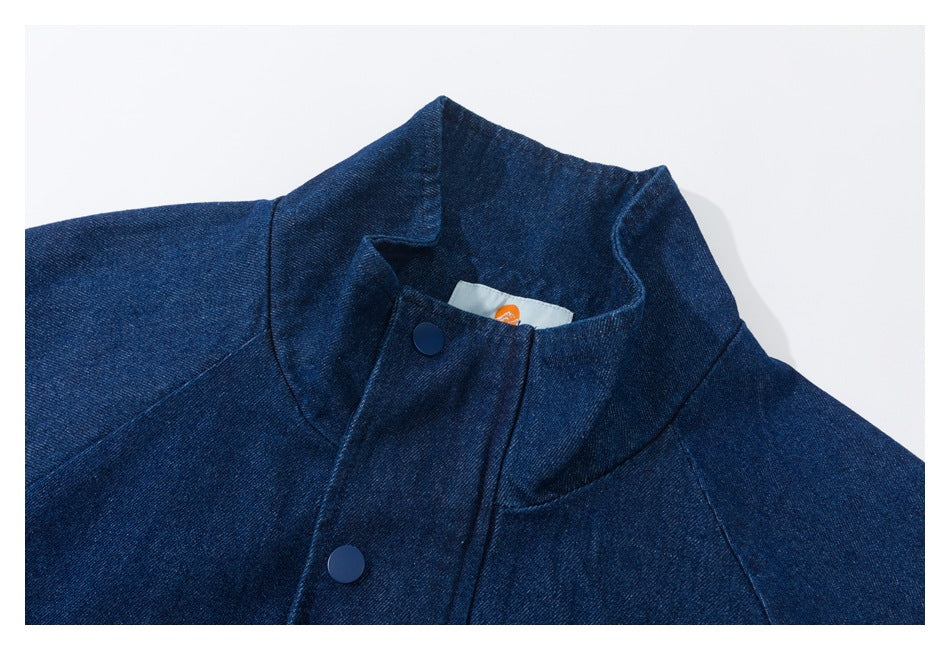 Close-up of a dark indigo denim jacket collar and snap-button front placket.