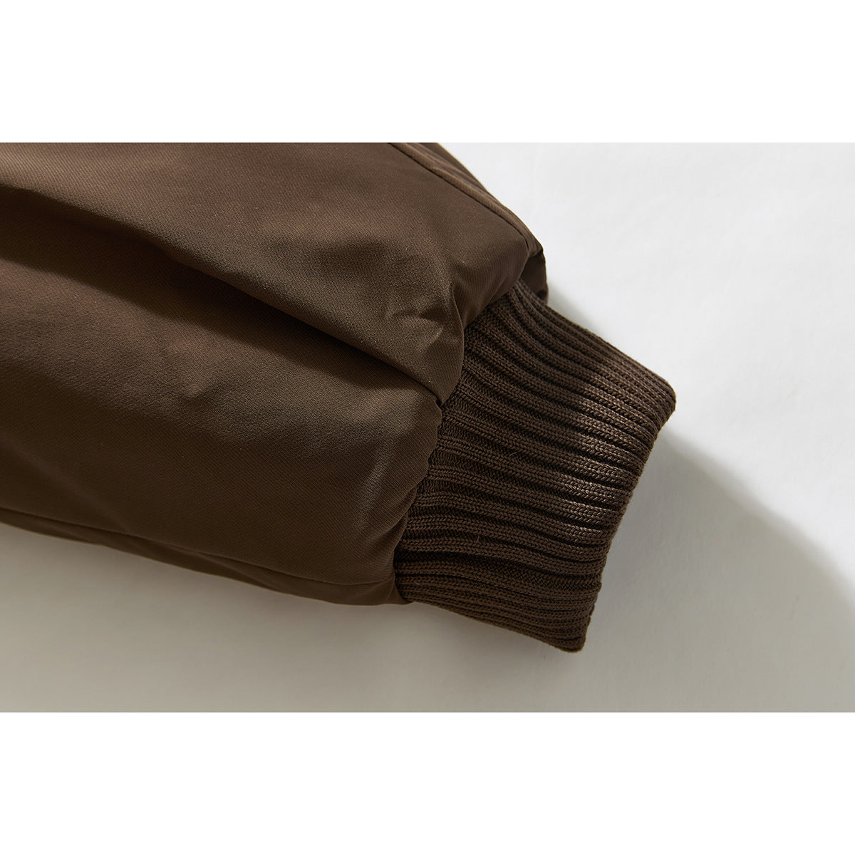 Close-up of a brown jacket sleeve ending in a dark rib-knit cuff.