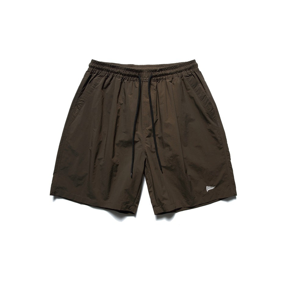Brown drawstring shorts with elastic waist and side pockets, flat lay front view
