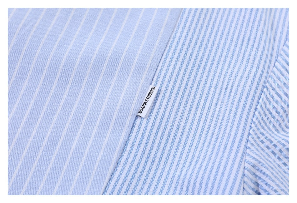Close-up of a light blue striped shirt with a small sewn label and a contrasting stripe panel.
