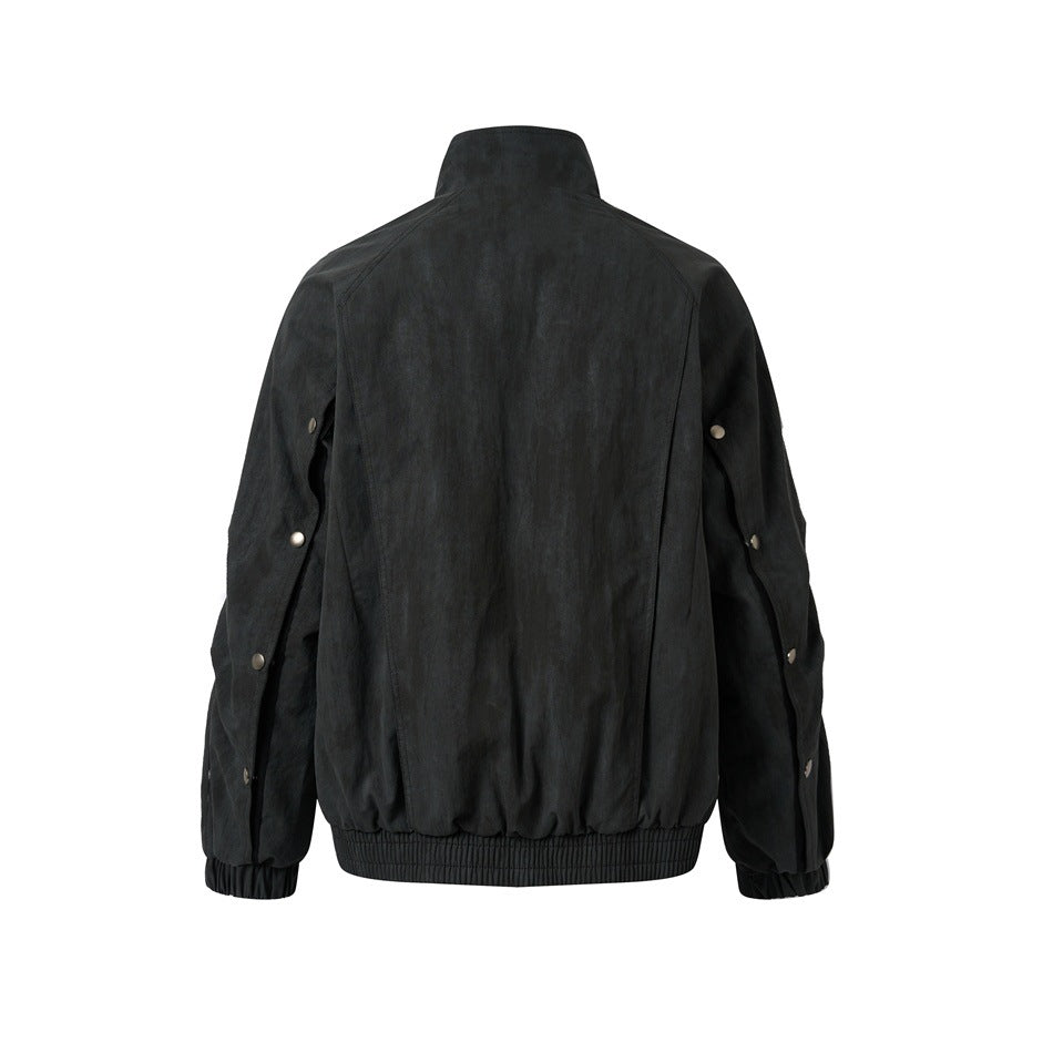 Black jacket back view showing raglan-style seams, snap buttons along the sleeves and elastic hem and cuffs