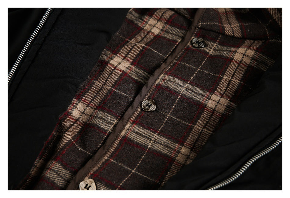 Close-up of a black jacket with a brown, cream, and red plaid buttoned panel beside a silver zipper.