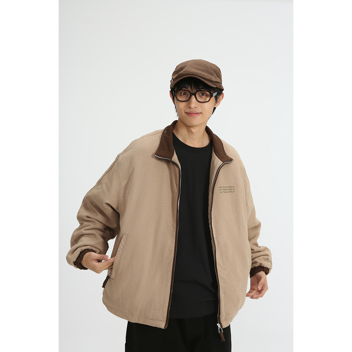 Closer front view of a model wearing a tan zip jacket with a dark brown collar and elastic cuffs.