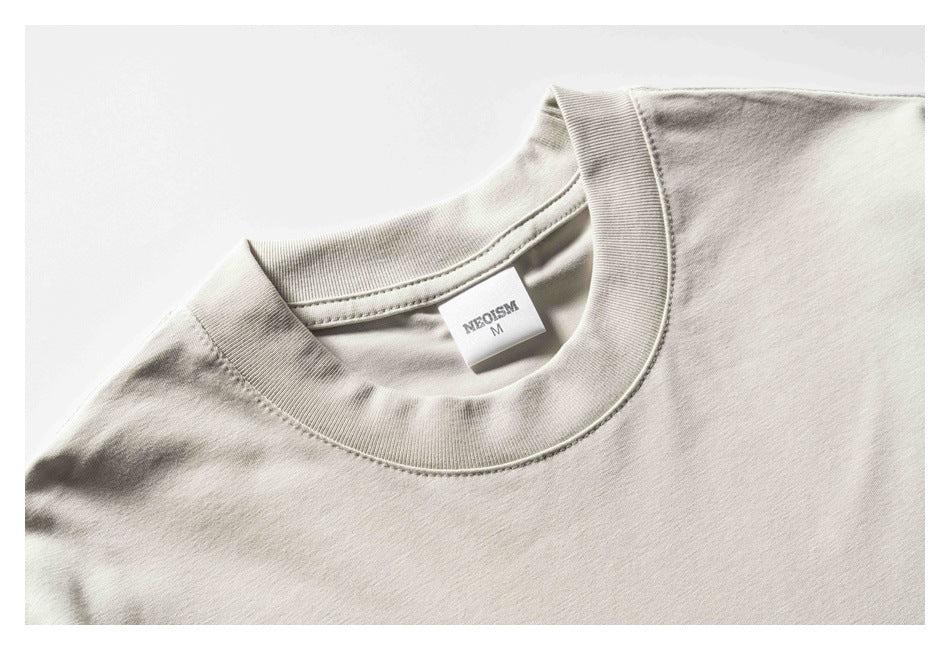 Close-up of a light beige T-shirt neckline with ribbed collar and a small printed neck label.