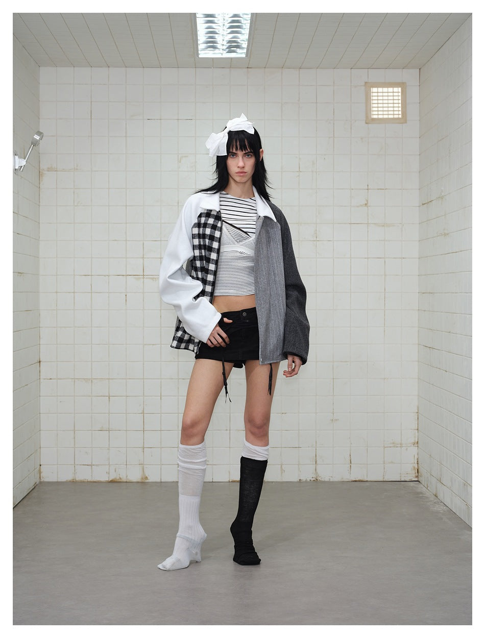 Model wearing an asymmetrical color-block jacket with a white sleeve, checked panel, gray pinstripe front, and charcoal