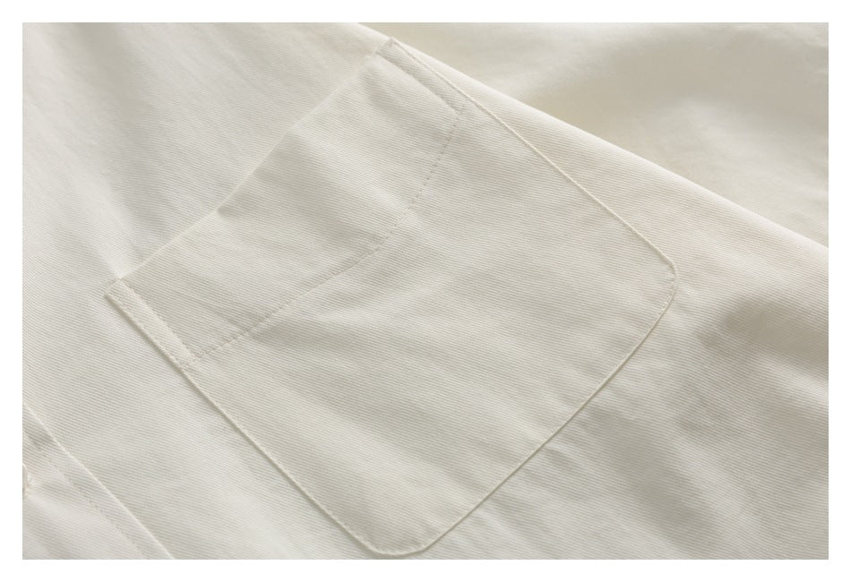 Close-up of a large stitched pocket on an ivory garment.