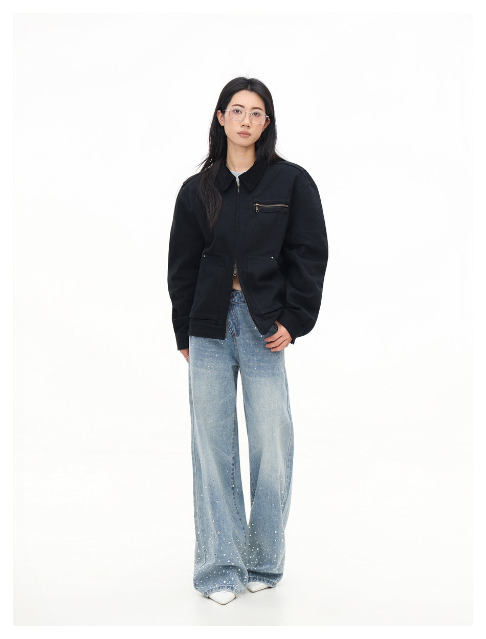 Full-length front view of a model in a black collared zip jacket with a chest zipper pocket and light-blue embellished jeans.