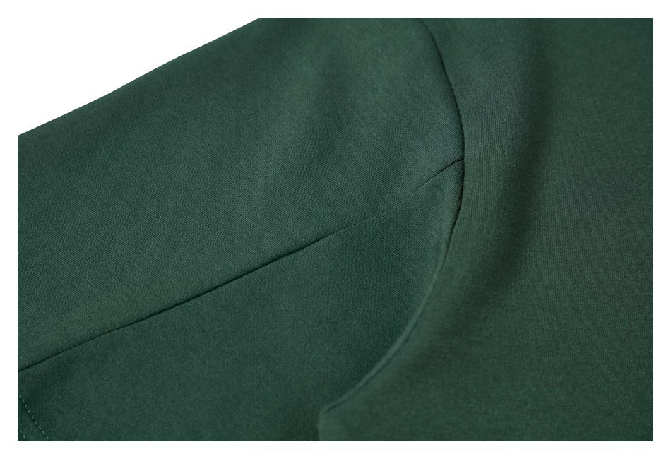 Close-up of dark green garment fabric and curved seam stitching.