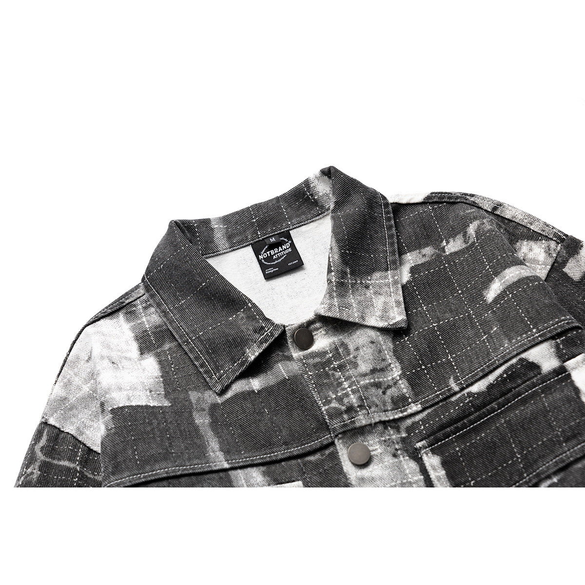Close-up of a charcoal and gray abstract plaid jacket collar, shoulder, and snap-button front.