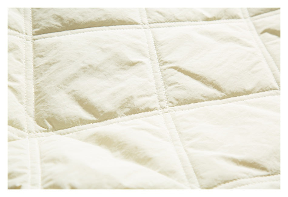 Close-up of ivory quilted fabric with rectangular stitched panels and a softly crinkled surface.