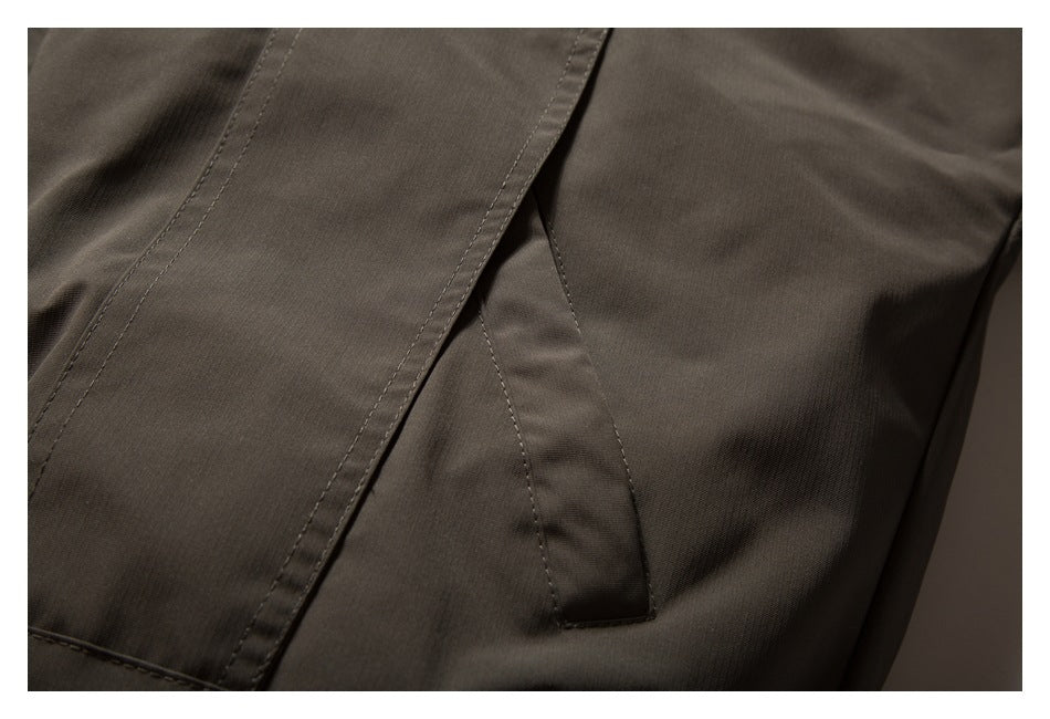 Close-up of a dark taupe jacket showing a pocket opening and stitched panels.
