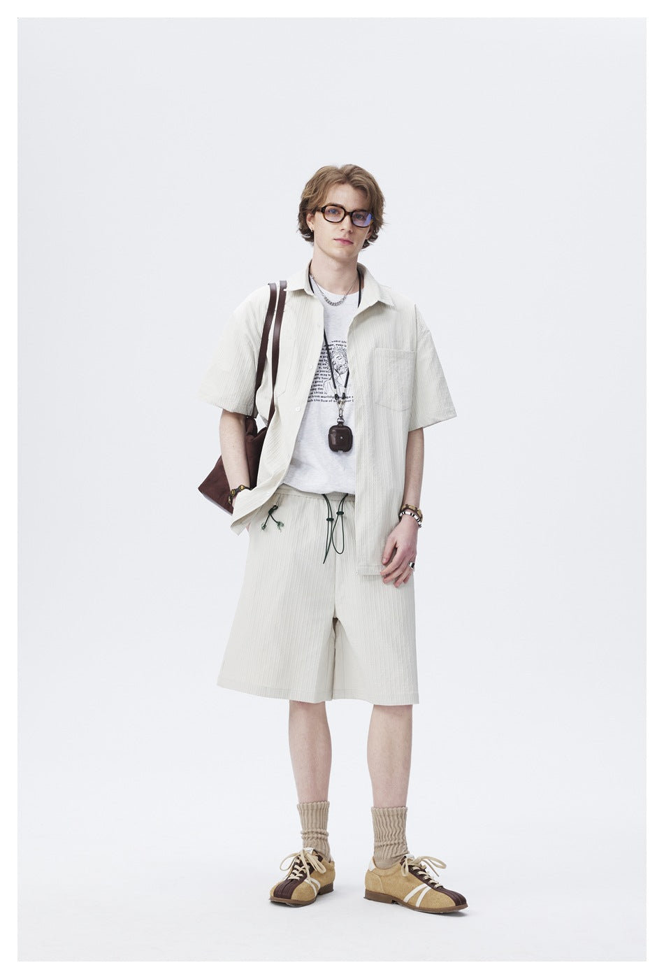 Full-length view of a model wearing an off-white short-sleeve shirt and matching drawstring shorts.