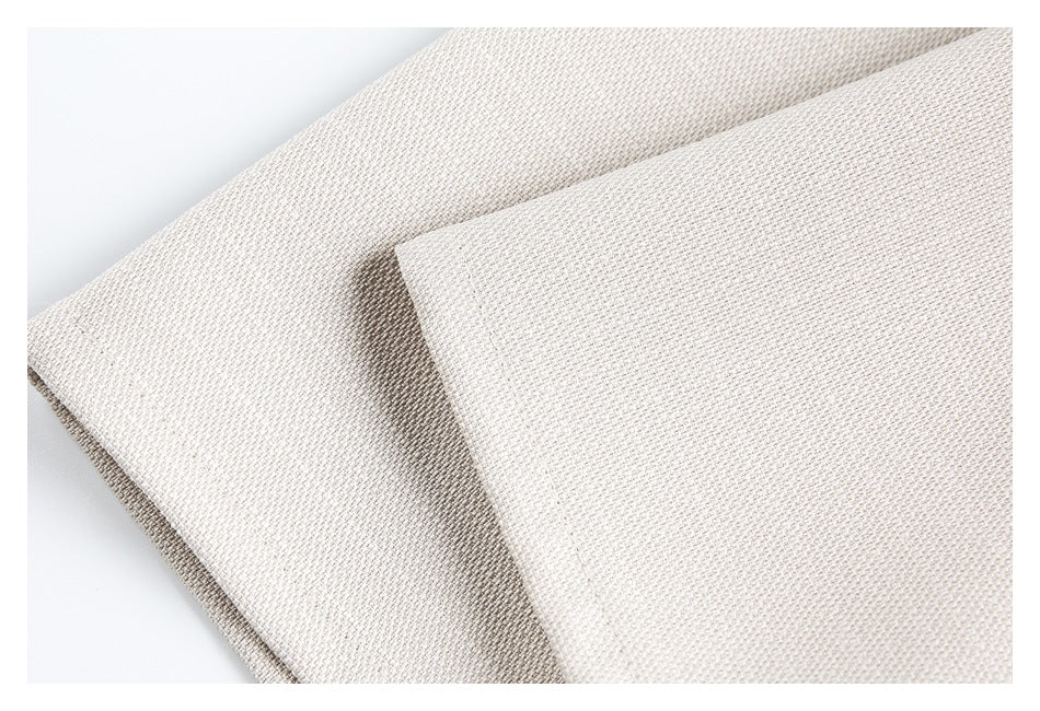 Close-up of light beige woven fabric folded to show its fine textured surface.