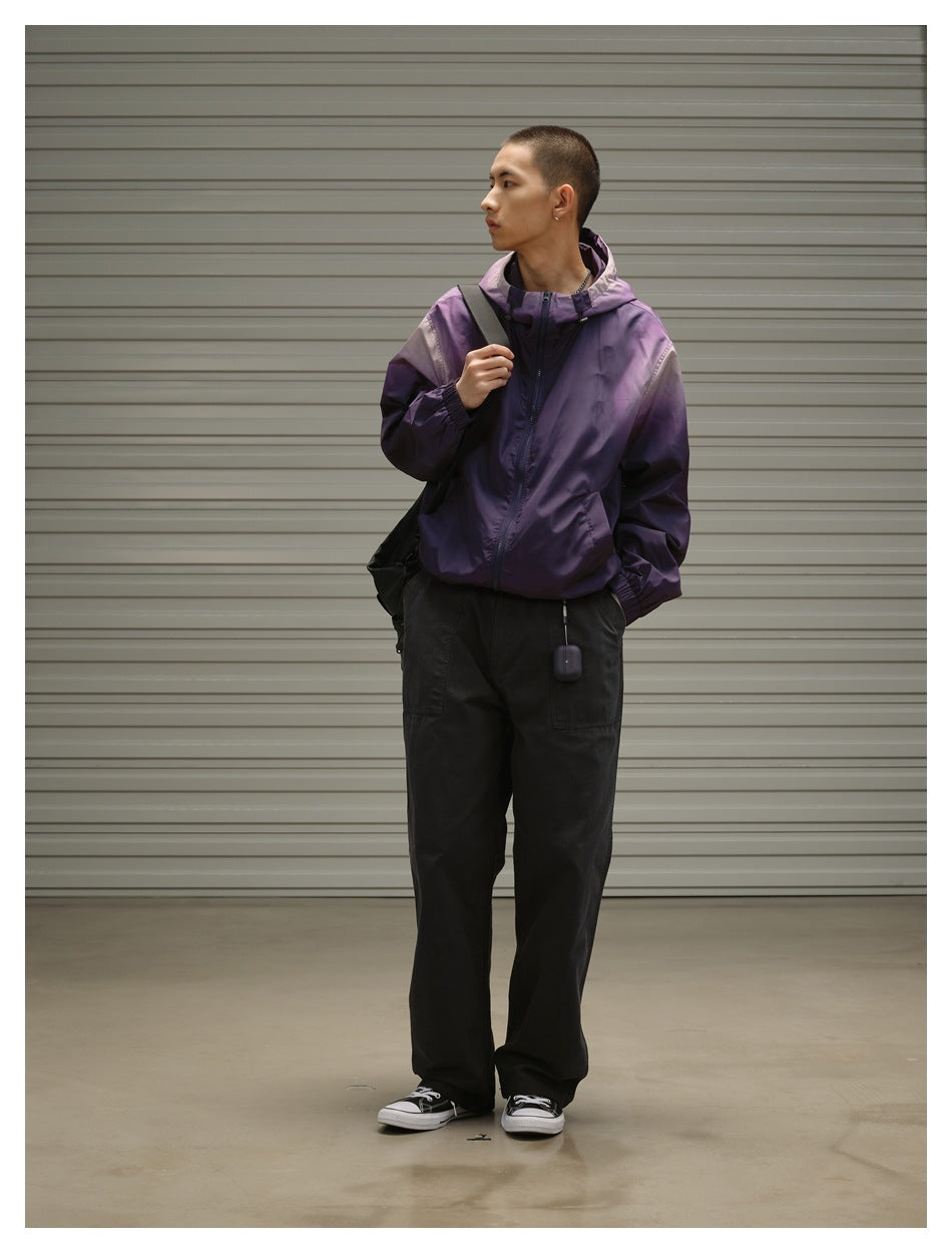 Model wearing a purple zip-front hooded jacket with elastic cuffs and loose black trousers.